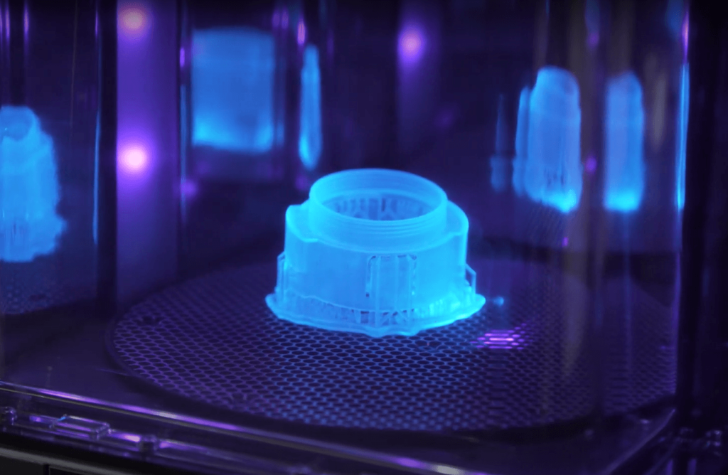 A 3D printer in operation, creating a three-dimensional object layer by layer. The printer's nozzle moves along a predefined path, depositing molten material onto the build plate. The image captures the additive manufacturing process, highlighting the precision and complexity involved in creating 3D-printed objects.