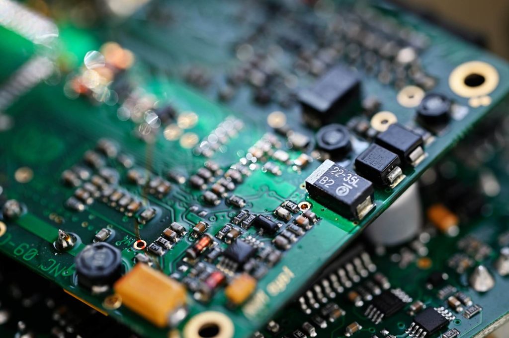 A close-up photograph of a modern electronic circuit board with various components soldered onto it. The board features intricate traces and patterns connecting the components, indicating a complex electrical design. The image conveys the concept of advanced technology and electronics manufacturing.