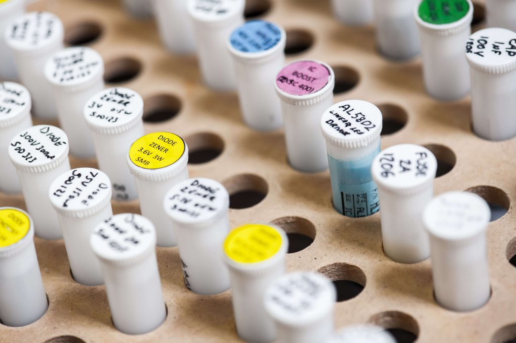 A close-up photograph showing a sampling process in progress. Various containers and equipment are arranged on a tabletop, indicating a sampling setup. The scene suggests a controlled environment for collecting and analysing samples in a laboratory or industrial setting